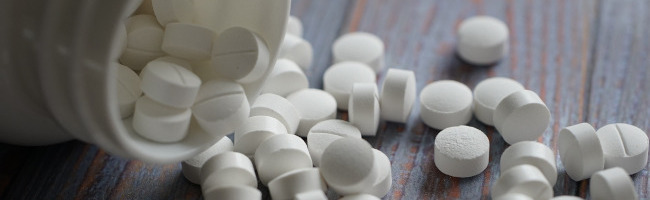 Aspirin pills spilled from a bottle - a visual representation of IT headaches